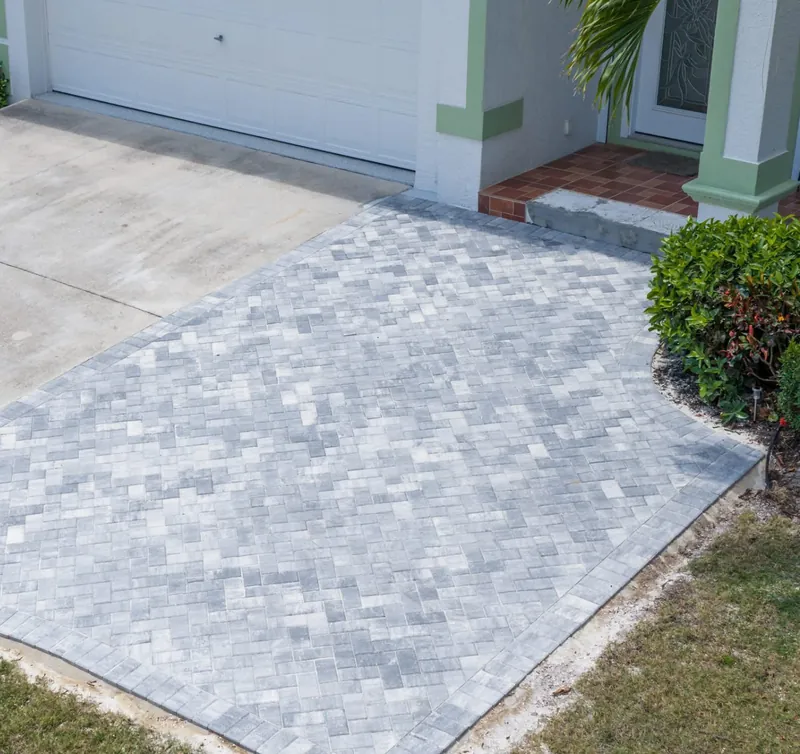 Gray blended paver driveway extension with a soldier-course border leading to the front entry