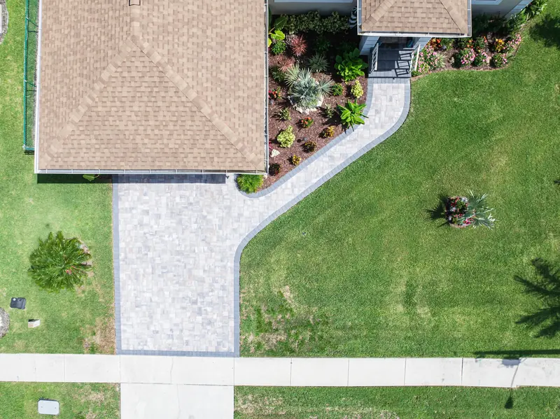 Overhead view of a green lawn, paver walkway and planted front bed